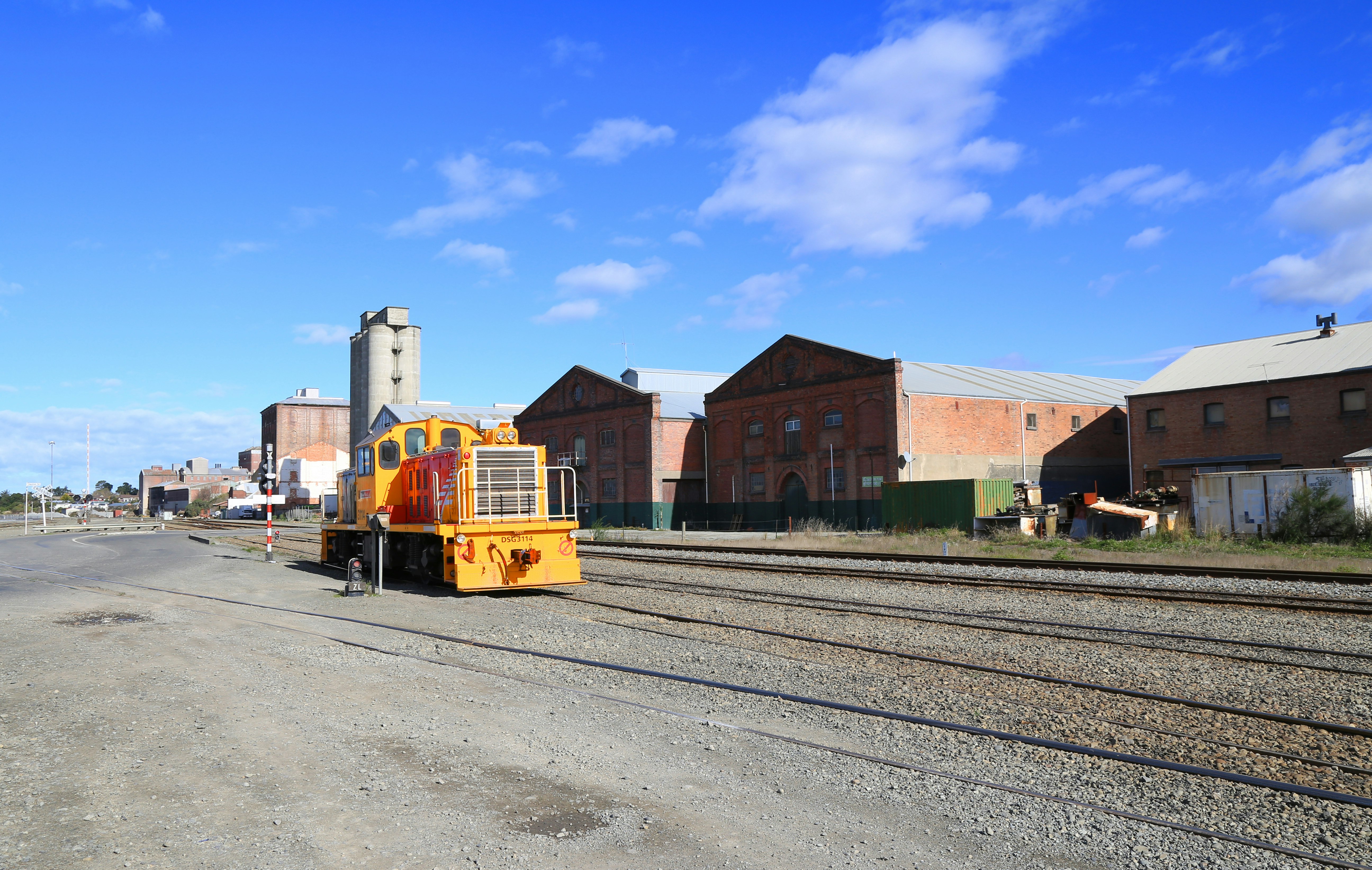 yellow and black train on rail road near brown building during daytime